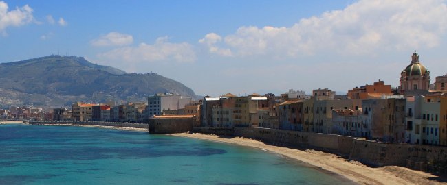 Costa con edifici storici e mare azzurro.