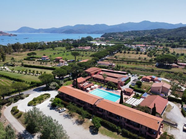 Vista dall'alto di hotel con piscina e montagne.