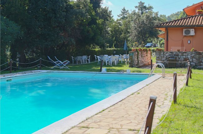 Piscina all'aperto con sedie e tavoli da esterno.