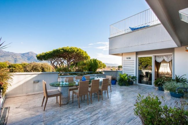 Terrazza con tavolo e sedie, vista su montagna alberata.