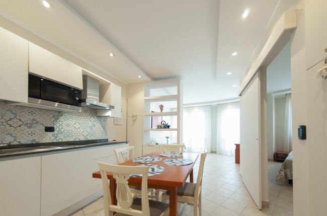 Cucina moderna con tavolo e sedie bianche.