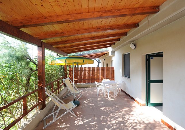 Terrazza coperta con sedie a sdraio e tavolo.
