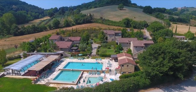 Vista aerea di un resort con piscina e colline.