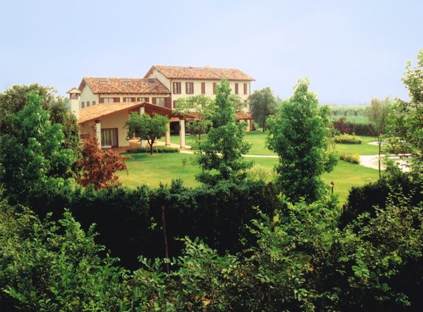 Grande casa immersa nel verde con alberi rigogliosi.