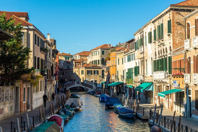 Canale veneziano con barche e case colorate.
