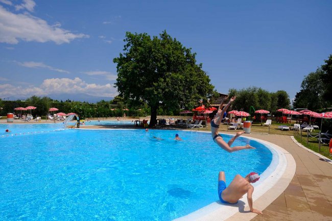 Persone giocano in piscina all'aperto.