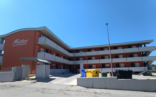 Edificio moderno a tre piani con balconi bianchi.