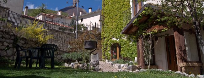 Casa con facciata verde, sedie da giardino in prato.