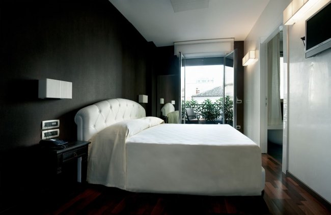 Camera moderna con letto matrimoniale bianco e balcone.