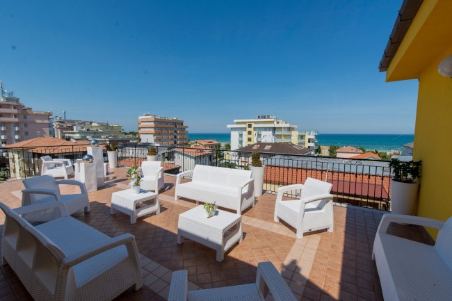 Terrazza vista mare con mobili bianchi.