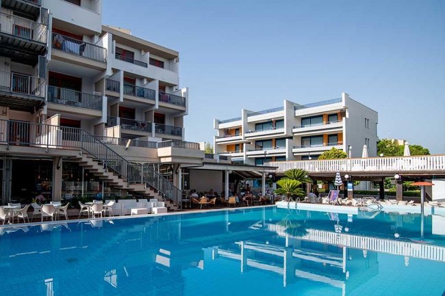 Complesso alberghiero con piscina all'aperto e sedie a sdraio.