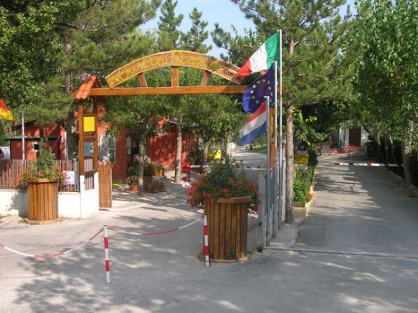 Ingresso di un campeggio con bandiere e vasi di fiori.