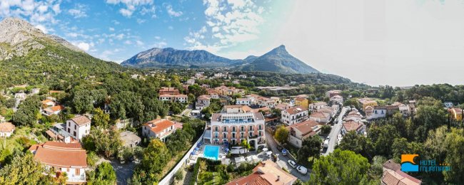 Vista aerea di un paesino con montagne e alberi.