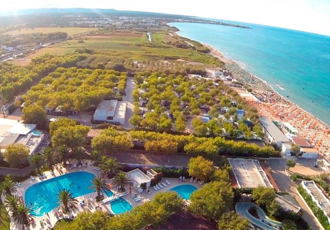 Vista aerea di un campeggio con piscine e spiaggia.