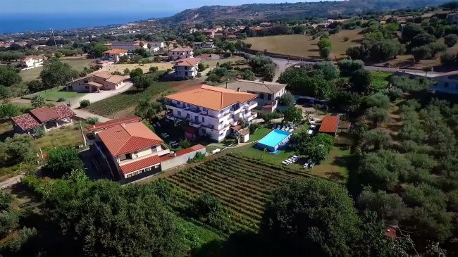 Panorama su case con piscina e campagna circostante.