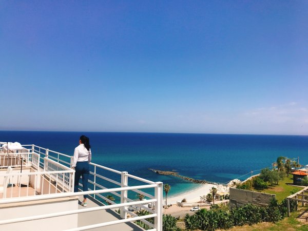 Persona su terrazza con vista mare blu.
