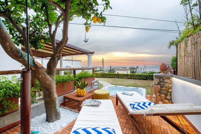 Terrazza con alberi e lettini vista mare.
