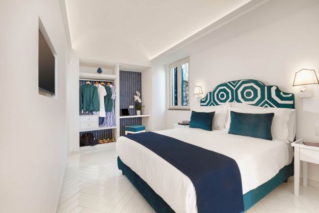 Camera da letto moderna con letto matrimoniale bianco e blu.