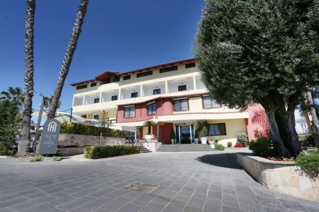 Hotel con palme e ingresso centrale.