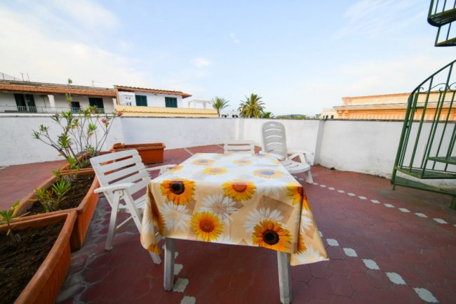 Terrazza con tavolo e sedie, vista su giardini.