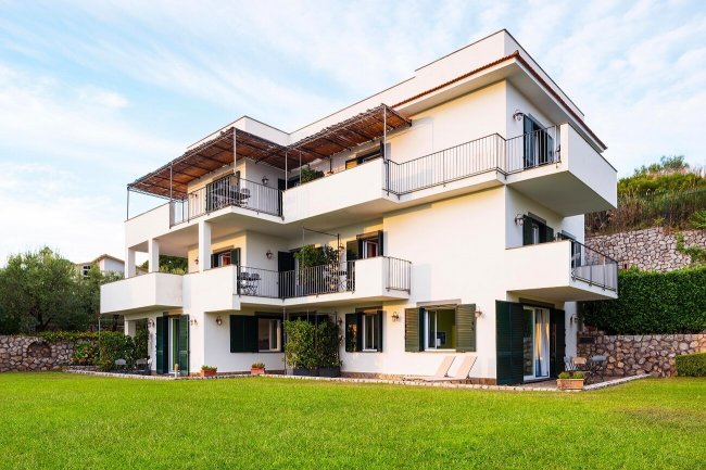Edificio moderno con balconi e ampio prato.