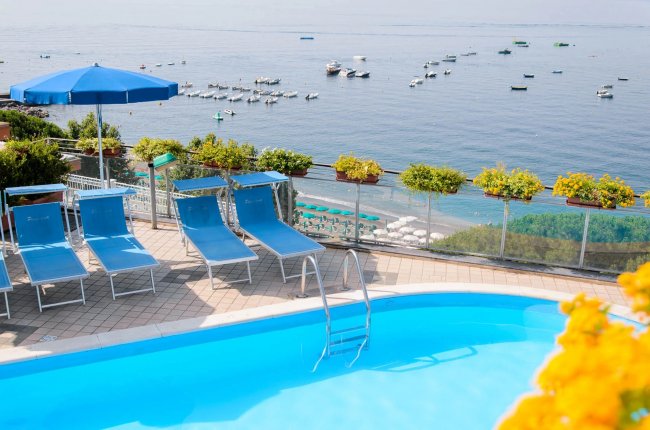 Piscina con lettini e vista mare.