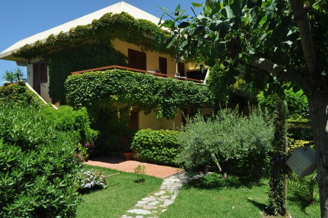Casa con edera e giardino curato.