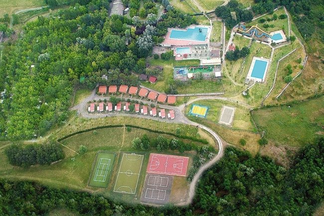 Vista dall'alto di un campeggio con piscine e campi sportivi.