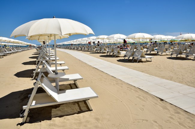 Spiaggia con ombrelloni bianchi e sdraio.