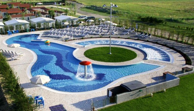Piscina con fontana centrale e lettini intorno.