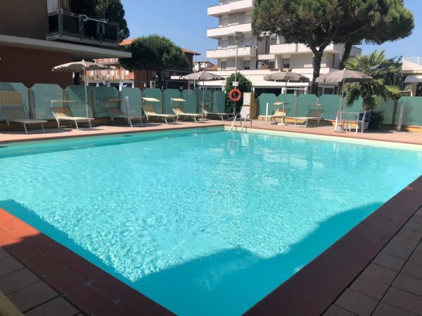 Piscina all'aperto con lettini e ombrelloni.