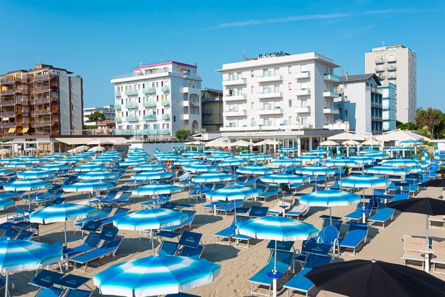 Spiaggia con ombrelloni blu e bianchi.