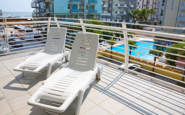 Due lettini in balcone con vista piscina e mare.