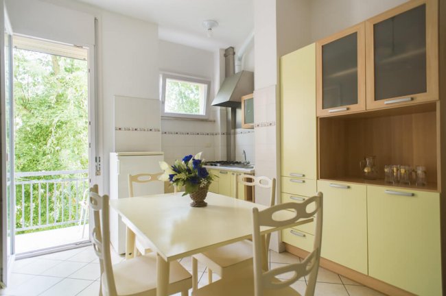 Cucina moderna con tavolo, sedie e porta aperta.