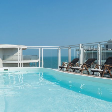 Piscina esterna con lettini e vista mare.