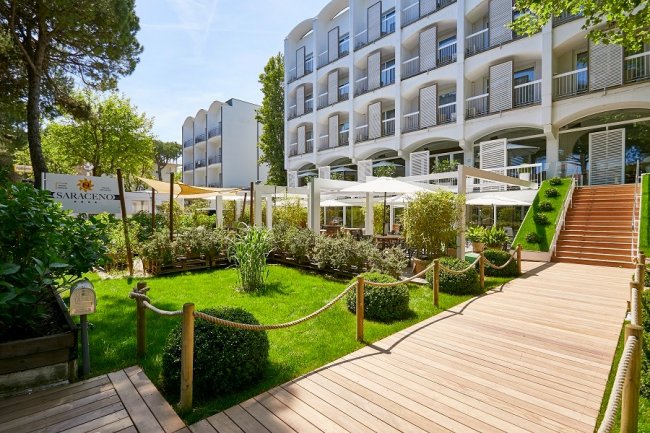 Giardino con passerella di legno e edificio bianco.