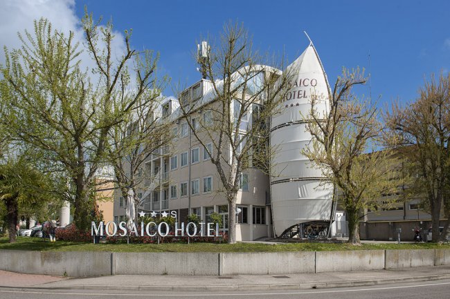 Mosaico Hotel tra alberi, cielo blu chiaro.