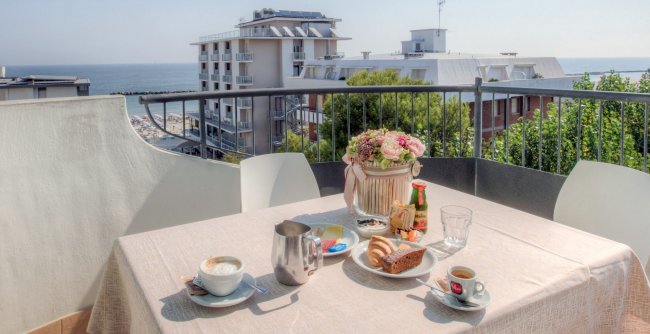 Tavolo all'aperto con colazione vista mare.