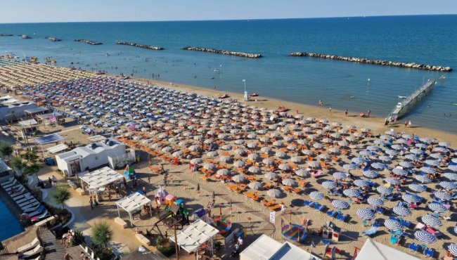 Lunga spiaggia con ombrelloni e bagnanti.