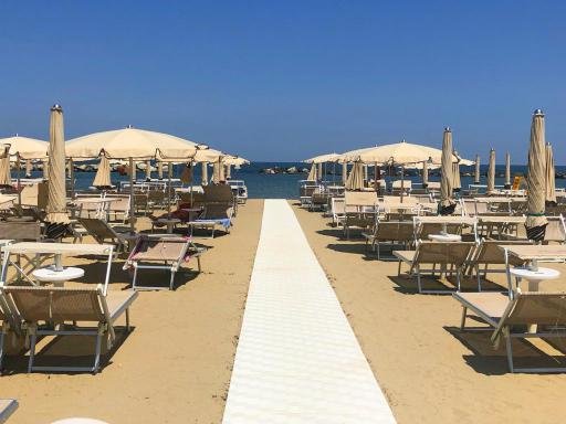 Spiaggia con ombrelloni e lettini in primo piano.