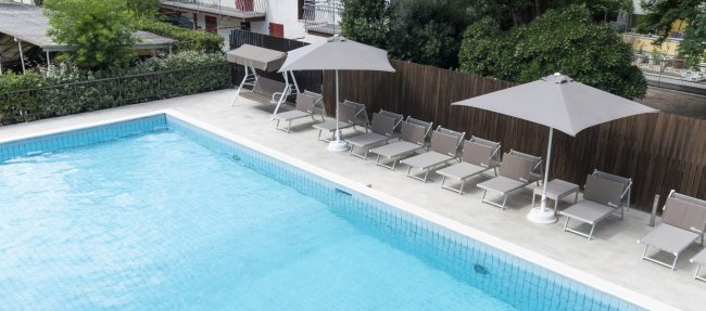 Piscina esterna con lettini e ombrelloni.