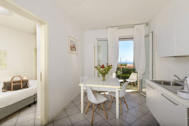 Sala da pranzo luminosa con tavolo, sedie e vista esterna.