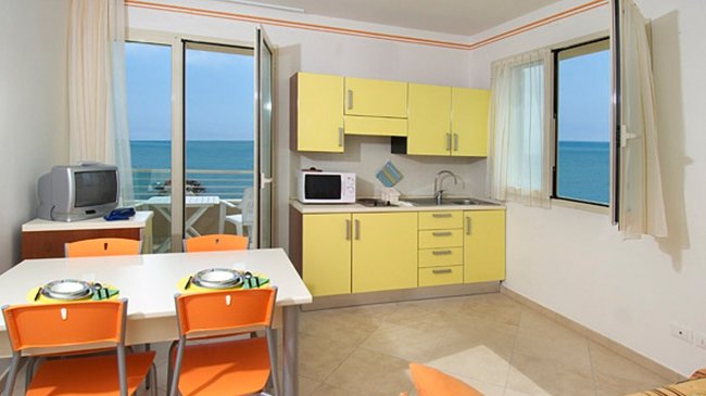 Cucina moderna gialla con vista mare e tavolo.