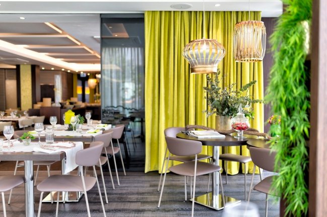 Ristorante moderno con sedie beige e tende gialle.