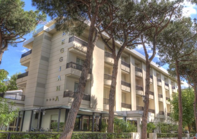 Edificio alberghiero con balconi, alberi davanti.