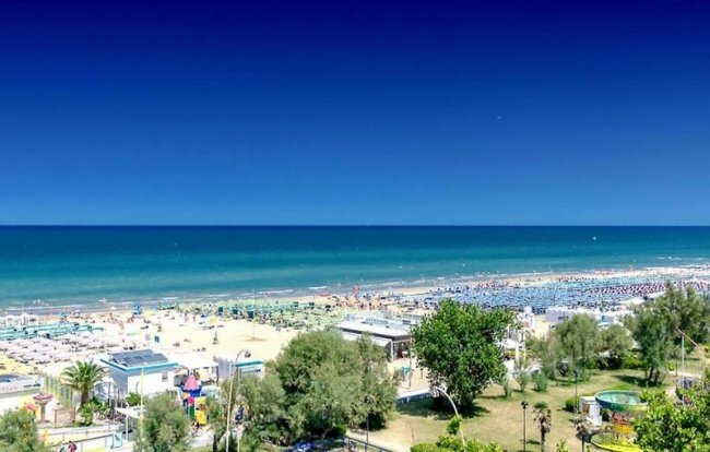 Spiaggia soleggiata con ombrelloni vista dall'alto.