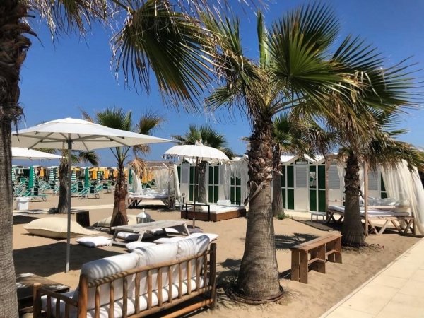 Area relax sulla spiaggia con palme e divani.