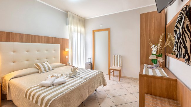 Camera moderna con letto matrimoniale, decorazioni a righe.