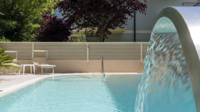 Piscina con cascata d'acqua e sedie a sdraio.