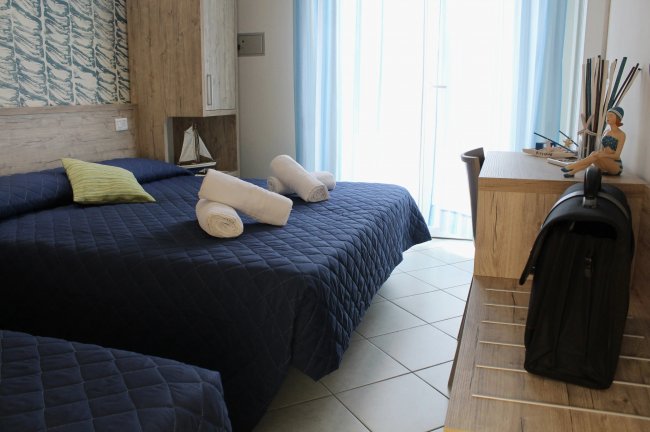 Camera con letto matrimoniale e tende azzurre.